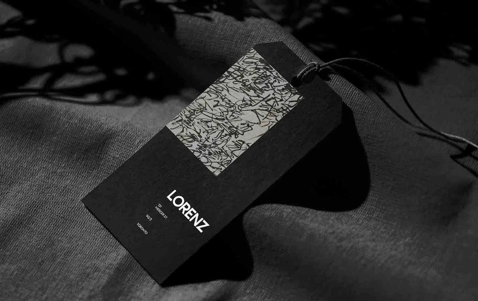 Black patterned hang tag with the Lorenz logo on draped fabric