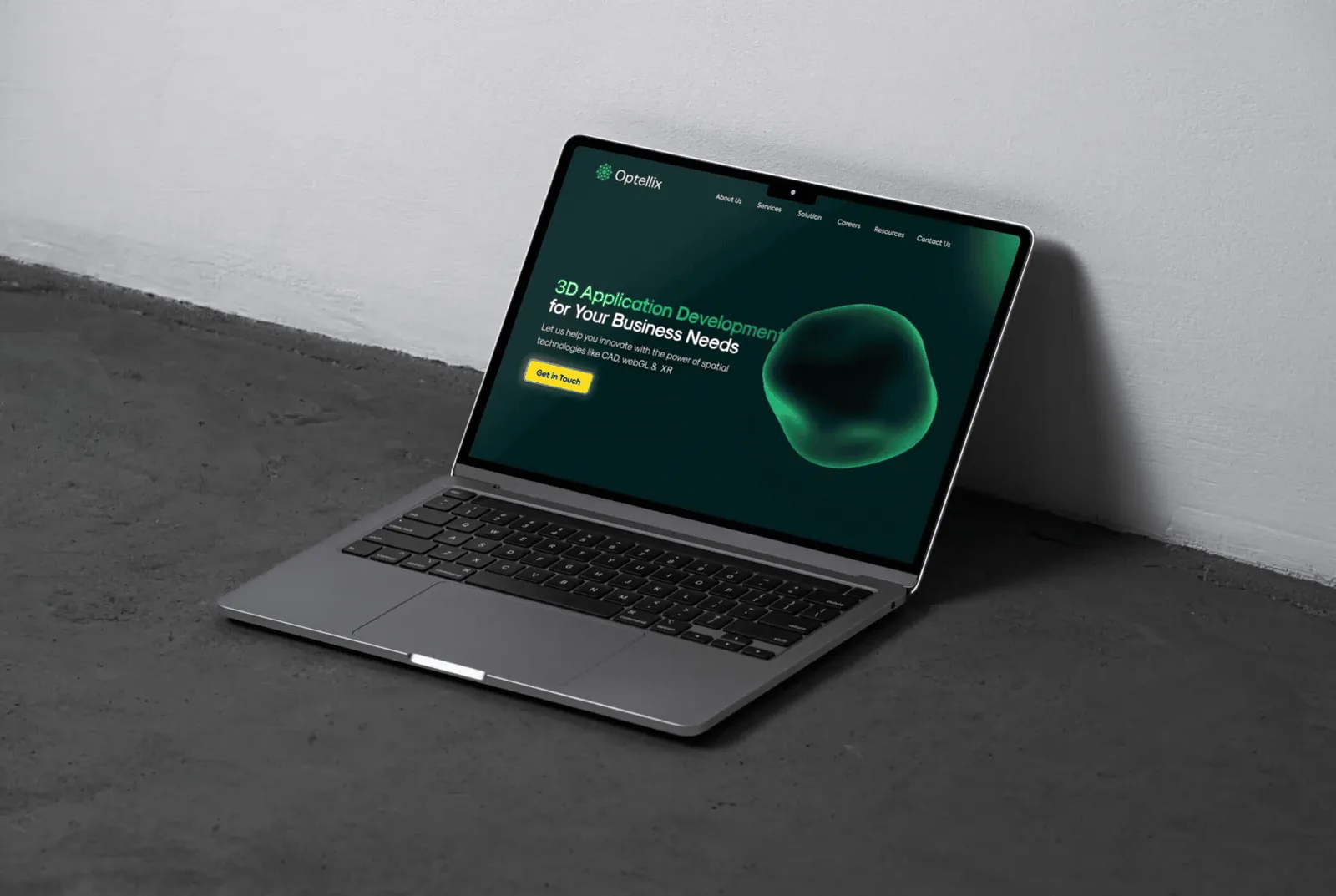 Laptop leaning against a white wall showing the Optellix homepage