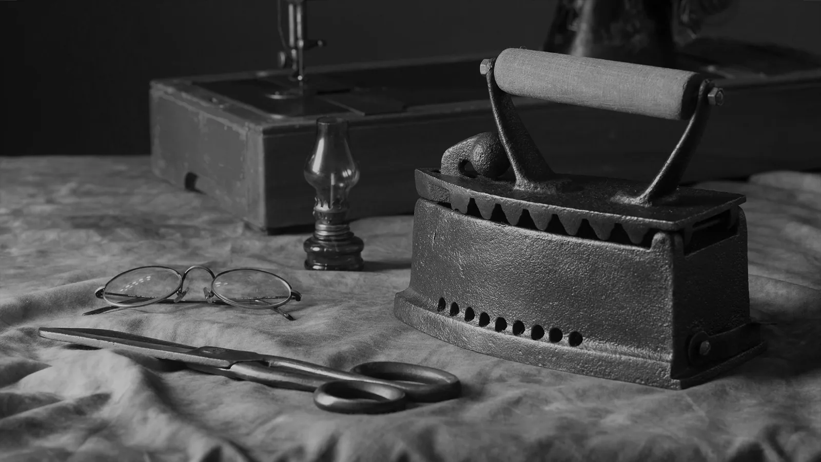 Black and white still life of an antique iron, scissors and spectacles