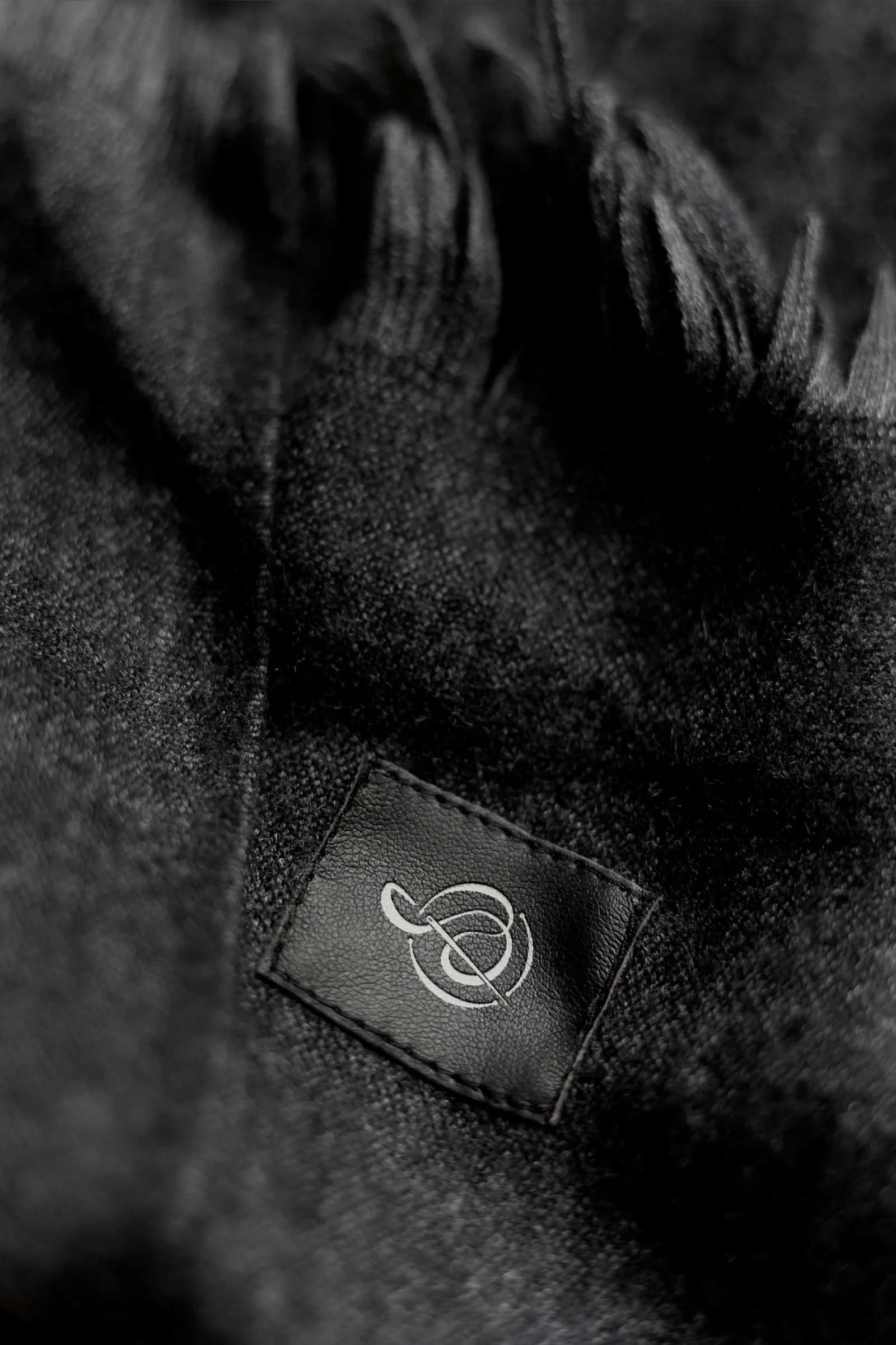 Close-up of a woven garment label with the gold monogram on dark fabric
