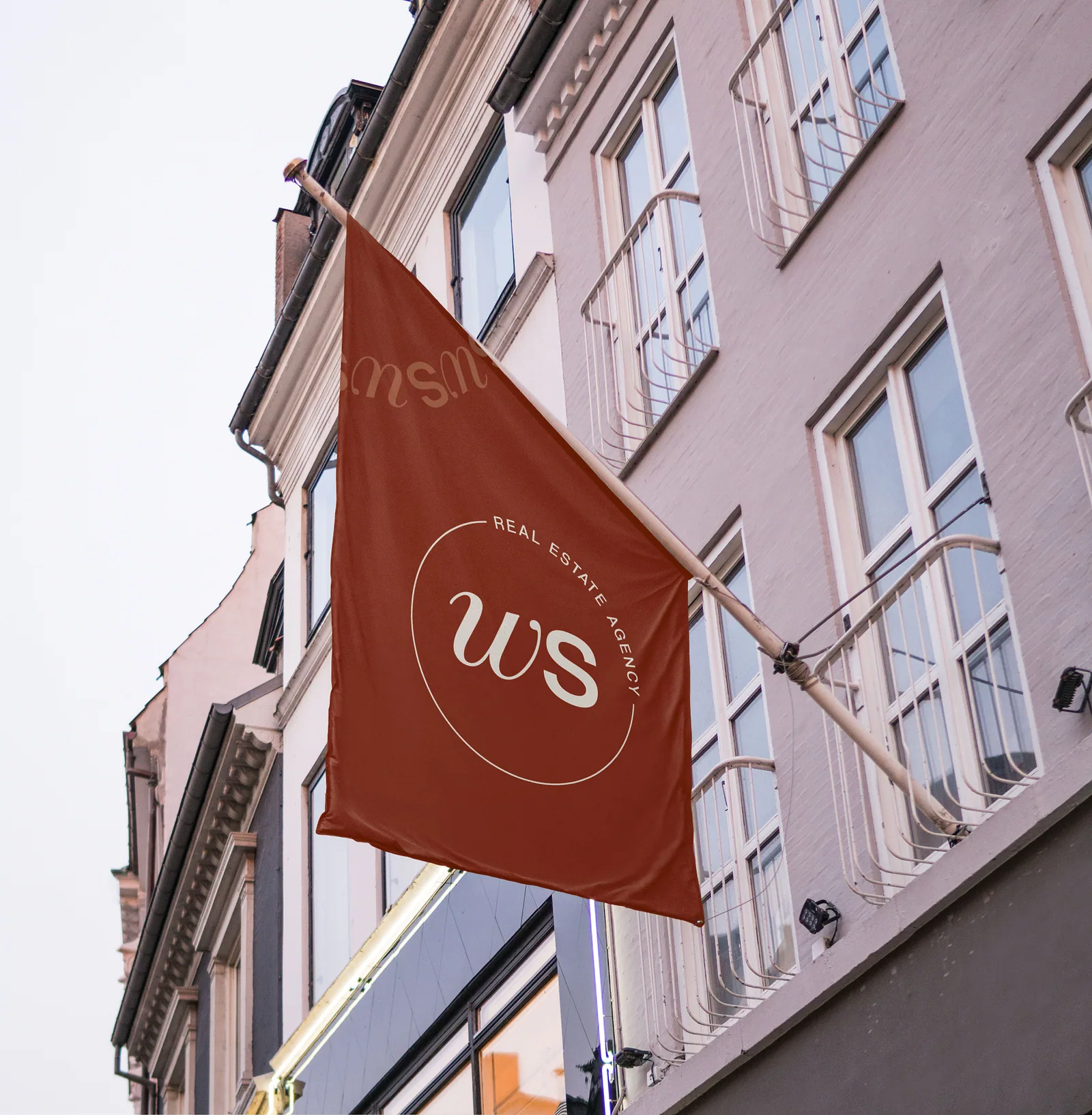 Rust brand flag with a circular WS monogram outside a pink building